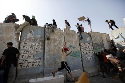 Iraqi_anti-government_protesters_climb_and_push_concrete_blast_walls_leading_to_the_heavily_guarded_Green_Zone_during_a_demonstration_in_Baghdad_IraqFriday_Feb_25_2011